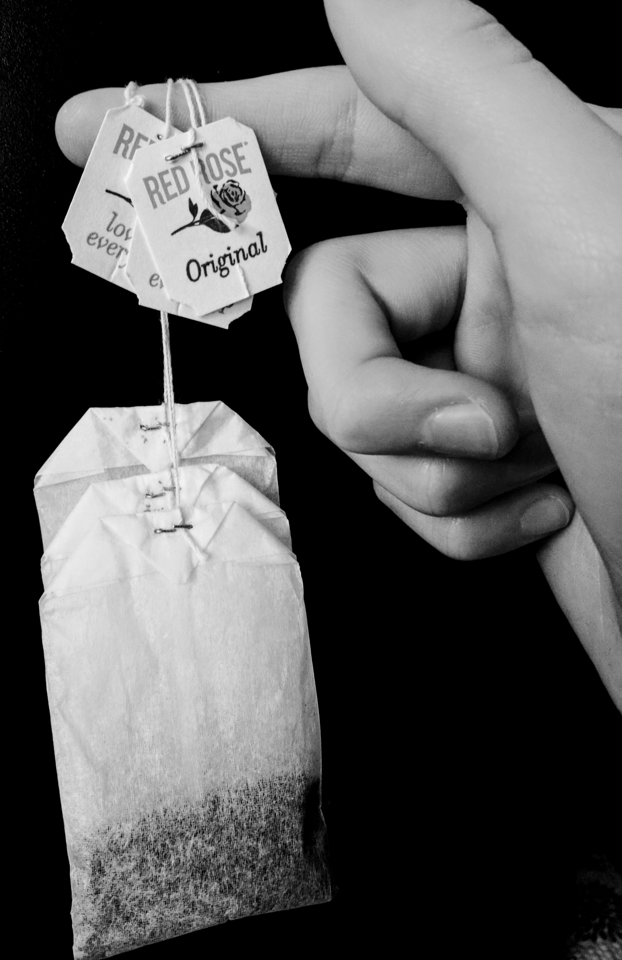 Black and White focus of person holding red rose tea bags